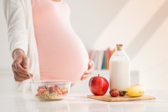 Pregnant woman choosing healthy foods for trimester-wise pregnancy nutrition.